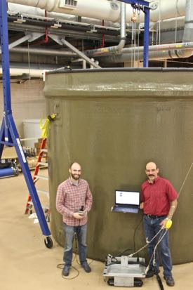 Dale McElhone and Paul Panetta with their “Acoustic Slick ROV,” in front of the 8,460-gallon tank they used for testing the vehicle inside VIMS’ Seawater Research Laboratory