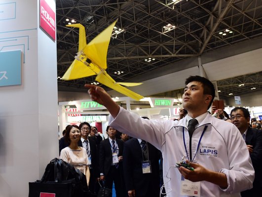 An employee of Japan's electronics parts maker Rohm demonstrates a remote controlled flying paper crane "Origami", weighing only 31g at the annual International Robot Exhibition in Tokyo on December 3, 2015. Some 450 companies and organisations are displaying their latest robots with 5,000 people expected to visit during the four-day event. AFP PHOTO / Yoshikazu TSUNO / AFP / YOSHIKAZU TSUNO (Photo credit should read YOSHIKAZU TSUNO/AFP/Getty Images)